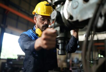 Worker at machine in factory, Metal industry worker at factory.